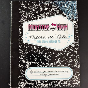 Könnte beinhalten: Ein schwarz-weißes Notizbuch mit einem Monster High-Logo und den Worten "Nefera de Nile this diary belongs to:" Das Notizbuch hat ein schwarz-weißes kariertes Muster und ein Spinnennetz-Design.