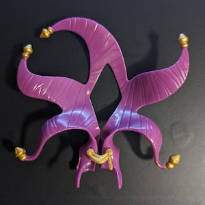 May include: Purple plastic jester hat with gold accents. The hat has a pointed top and two long, curved horns.