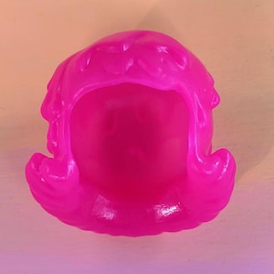 May include: A bright pink plastic doll wig with a short, curly style.