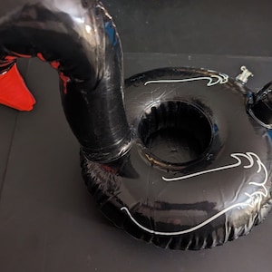 Puede incluir: Soporte inflable negro en forma de cisne con pico rojo y detalles blancos. El cisne tiene una abertura circular para una bebida y está diseñado para flotar en el agua. Un accesorio divertido para fiestas en la piscina.