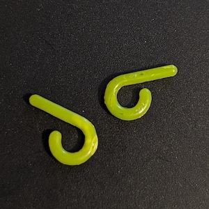 Puede incluir: Dos ganchos de plástico verde lima en forma de bastón de caramelo. Los ganchos tienen forma de bastón de caramelo y tienen un pequeño bucle en el extremo.