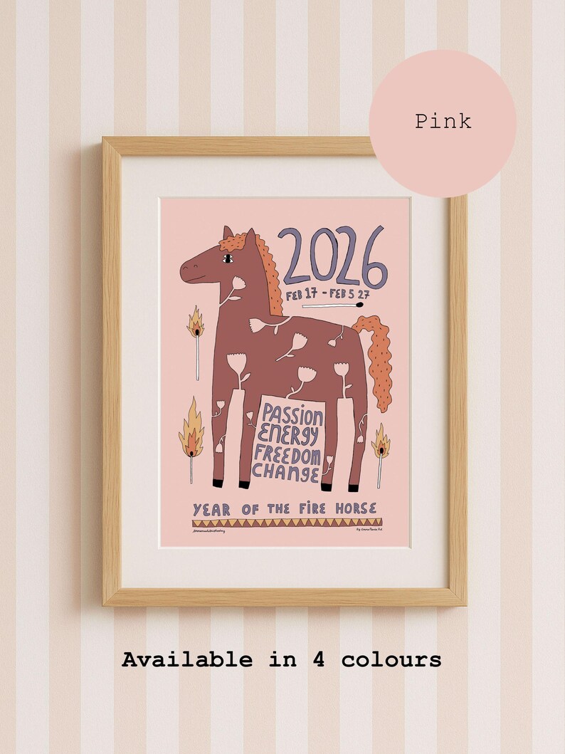 A framed art print on a pink background featuring a brown horse illustration with white flower outlines. Text includes 2026, FEB 17 - FEB 5 27, PASSION ENERGY FREEDOM CHANGE, and YEAR OF THE FIRE HORSE. Matches are depicted with flames on the sides.