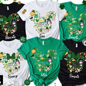 May include: A collection of St. Patrick's Day t-shirts in black, white, and green. Each shirt features a Mickey Mouse head design filled with festive graphics and character illustrations. Names are printed below the design.