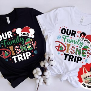 Puede incluir: Camisetas negras y blancas con el texto "OUR Family DISNEY TRIP" en un dise&ntilde;o festivo. El dise&ntilde;o incluye un gorro de Pap&aacute; Noel, orejas de Mickey Mouse y los nombres "James" y "Sophie". Tambi&eacute;n se incluye una bolsa de tela gratuita de 38x38 cm.