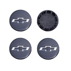 Peut inclure: Quatre enjoliveurs noirs avec le logo Chevrolet argenté. Trois sont face visible, et un est à l'envers, révélant l'arrière. Les enjoliveurs sont ronds et ont une finition brillante.