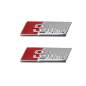 May include: Two silver and red S line car emblems. Each emblem has a rectangular red section on the left and the silver S line logo on the right. The emblems are on a white background.