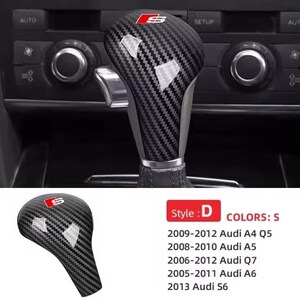 Op de afbeelding: Carbon fiber stijl D versnellingspookknop met een rood en wit "S" logo. Compatibel met Audi A4, A5, Q7, A6 en S6 modellen van 2005-2013. De knop heeft een getextureerd, geweven patroon.