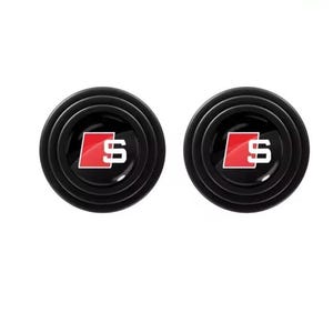May include: Two black car door protectors with a red and white "S" logo. The protectors have a circular design with concentric rings and a glossy finish. The background is plain white.