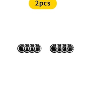Puede incluir: Dos insignias con el emblema de Audi en negro y plata. Las insignias presentan el icónico diseño de cuatro anillos entrelazados. Un óvalo amarillo encima de las insignias dice "2pcs".