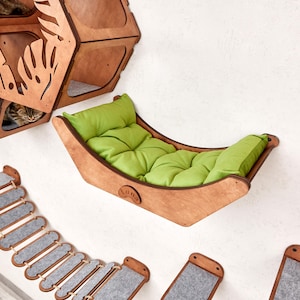 Puede incluir: Juego de muebles para gatos de madera, que incluye una hamaca con un coj&iacute;n verde, un &aacute;rbol para gatos de varios niveles y un puente. La hamaca para gatos mide aproximadamente 61 cm de largo. El conjunto est&aacute; montado en una pared blanca.