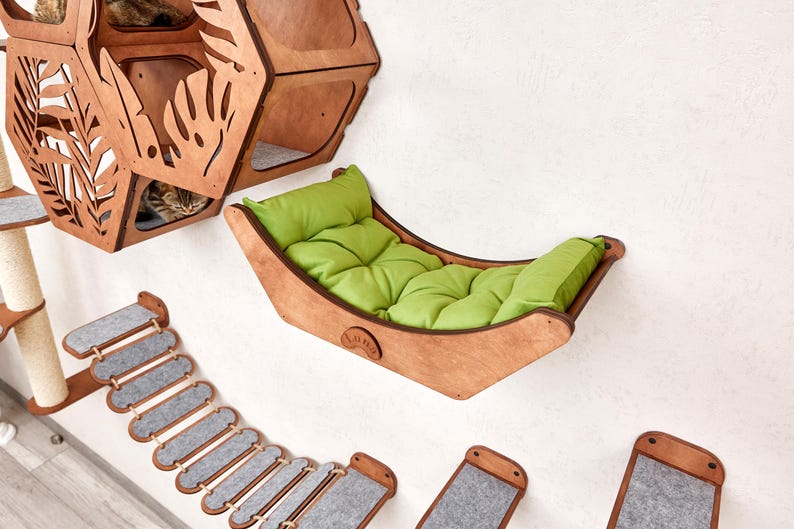 Puede incluir: Juego de muebles para gatos de madera, que incluye una hamaca con un coj&iacute;n verde, un &aacute;rbol para gatos de varios niveles y un puente. La hamaca para gatos mide aproximadamente 61 cm de largo. El conjunto est&aacute; montado en una pared blanca.