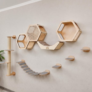 Puede incluir: Un conjunto de muebles para gatos de madera montado en una pared beige. El conjunto incluye estantes hexagonales, un puente curvo, escalones y un rascador. El &aacute;rbol para gatos y los estantes son de madera clara con superficies alfombradas grises.