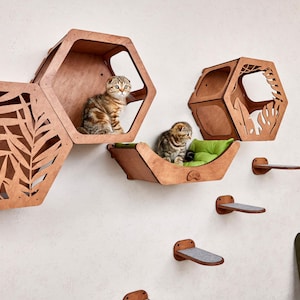 Puede incluir: Juego de muebles para gatos de madera con m&uacute;ltiples casas hexagonales y escalones. Dos gatos est&aacute;n sentados en las casas. Las casas para gatos son marrones con recortes de hojas. Los escalones son marrones con almohadillas grises.