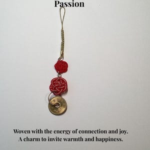 Op de afbeelding: Een rode Mizuhiki-bedel met een gouden ketting en een Japanse munt. De bedel heeft twee geweven rode knopen en de tekst "Red Mizuhiki - For Love & Passion". De tekst "Woven with the energy of connection and joy. A charm to invite warmth and happiness."