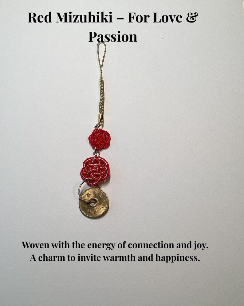 Op de afbeelding: Een rode Mizuhiki-bedel met een gouden ketting en een Japanse munt. De bedel heeft twee geweven rode knopen en de tekst "Red Mizuhiki - For Love & Passion". De tekst "Woven with the energy of connection and joy. A charm to invite warmth and happiness."