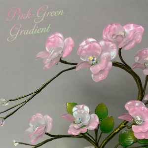 May include: A decorative wire tree sculpture featuring translucent pink flowers with iridescent centers and green leaves. The branches are made of thin, dark wire. The text "Pink-Green Gradient" is visible in the upper left corner of the image.