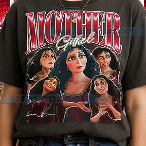 以下が含まれることがあります： 映画「塔の上のラプンツェル」のキャラクター、マザー・ゴーテルのグラフィックが描かれた濃いグレーのTシャツ。「MOTHER」の文字は赤色の様式化されたフォントで、「Gothel」は筆記体で描かれています。画像には、キャラクターの複数の描写が示されています。