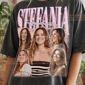 Pode incluir: T-shirt cinzenta escura com o nome "STEFANIA" em rosa e "Spampinato" por baixo. A t-shirt apresenta várias imagens de uma mulher. O texto "PEPPER COMFORT COLORS" está impresso na parte inferior.