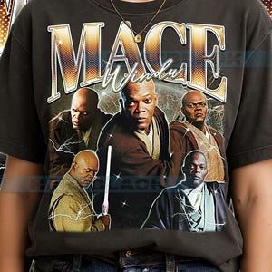 Peut inclure: T-shirt gris foncé avec un graphisme de Mace Windu et le texte "Mace Windu" en or. Le design comprend plusieurs images du personnage avec des éclairs, créant un style vintage.