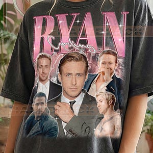 May include: Dark gray t-shirt featuring a collage of images of Ryan Gosling, with the name "RYAN" in pink, glittery letters. The shirt also has the text "Gosling" in a cursive font. The words "PEPPER COMFORT COLORS" are printed at the bottom.