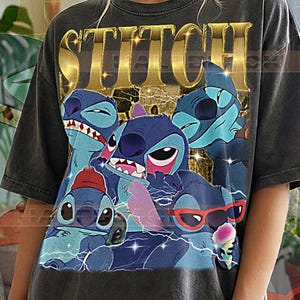 May include: Dark gray t-shirt featuring a graphic of Stitch from Lilo & Stitch. The word "STITCH" is in gold lettering above the character illustrations. The shirt has a distressed look and the text "PEPPER COMFORT COLORS" is at the bottom.