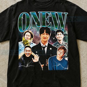 Puede incluir: Camiseta negra con la palabra "ONEW" en una fuente retro sobre un collage de cinco personas. El diseño tiene una estética vintage con un fondo colorido con temática espacial.