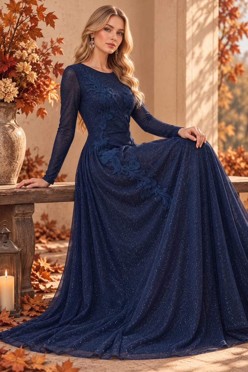 May include: A floor-length navy blue long-sleeve gown featuring a shimmering glitter finish and intricate floral applique detailing that extends from the shoulder down to the waistline, with a round neckline and a full, flowing skirt.