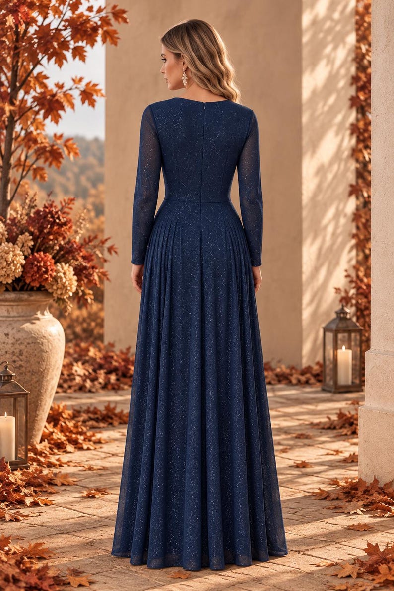 May include: A floor-length navy blue gown with long sleeves and a subtle glitter finish. The dress features a fitted bodice, a high neckline, and a pleated skirt that flows from the waist to the floor, creating a structured and elegant silhouette.