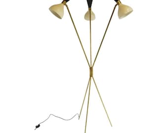 Può includere: Lampada da terra in stile moderno della metà del secolo con tre luci. La lampada presenta una struttura color ottone e tre paralumi a forma di cono. I paralumi sono color crema con dettagli neri. La lampada ha un cavo di alimentazione nero.