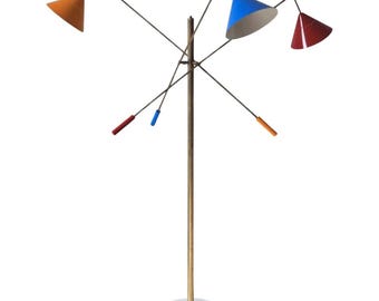 May include: A modern floor lamp with a white marble base and a brass pole. The lamp features four cone-shaped shades in orange, blue, and red, each attached to thin metal arms. The arms have colored accents. The lamp is a unique piece of home decor.