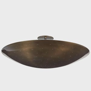 May include: A bronze-colored, oval-shaped ceiling light fixture with a polished finish. The fixture has a series of small, evenly spaced lights across its surface. A circular, chrome-colored mounting plate is attached to the top.