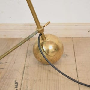 May include: A vintage brass desk lamp with a spherical base and adjustable arm. The lamp features a gold finish and a black power cord. The design is mid-century modern, with a focus on functionality and style.