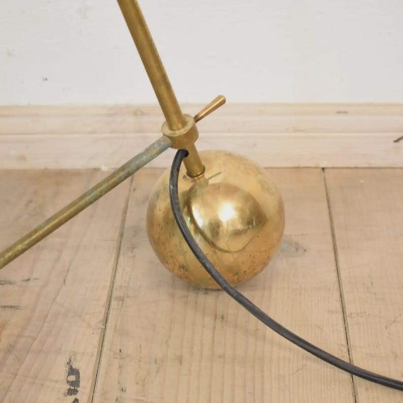 May include: A vintage brass desk lamp with a spherical base and adjustable arm. The lamp features a gold finish and a black power cord. The design is mid-century modern, with a focus on functionality and style.