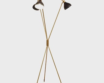 May include: A mid-century modern floor lamp with a tripod base and three adjustable light heads. The lamp features a gold-toned metal frame and black and cream-colored shades. The light heads have a perforated design.
