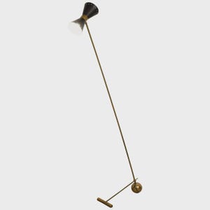 May include: A mid-century modern floor lamp with a black and gold conical shade. The lamp has a slender, brass-colored stem and a small, round base. The lamp's design is minimalist and elegant, suitable for a living room or office.