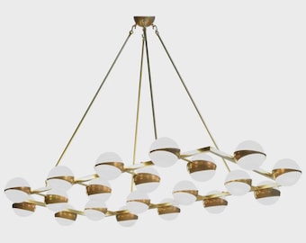May include: A modern chandelier featuring multiple frosted glass globes with brass accents. The fixture is suspended from the ceiling by thin metal rods and chains, creating a geometric design. The overall color scheme is gold and white.