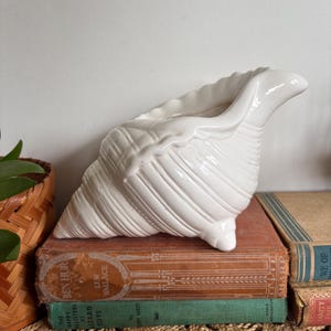 May include: A set of three ceramic mugs with a speckled, matte finish. Each mug is in a different colour: light blue, cream, and grey. The mugs have a simple, modern design with a rounded shape and a comfortable handle.