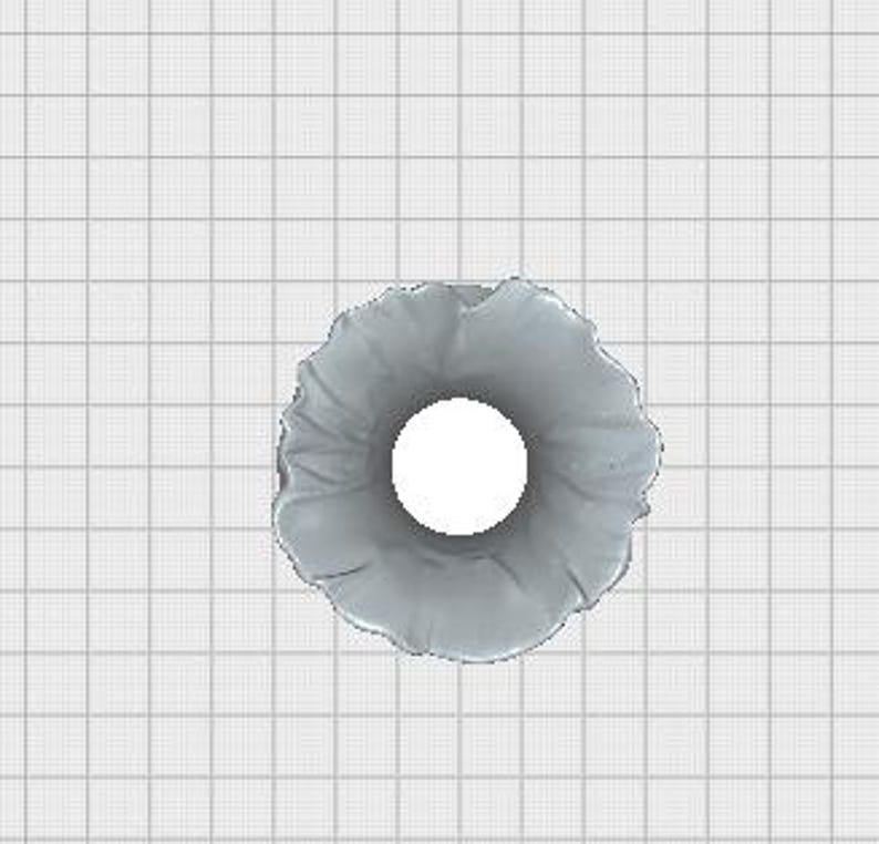 May include: A top-down view of a gray, ruffled scrunchie with a white center. The scrunchie is made of a soft, textured fabric and is set against a grid background.
