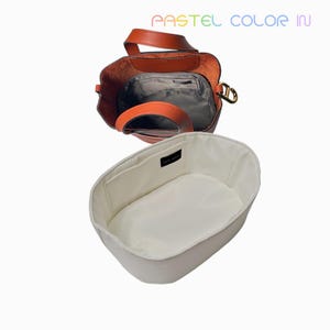 May include: An open, orange leather tote bag with a matching handle and a gray interior. Below it is a white oval-shaped bag organizer. The text "PASTEL COLOR IN" is at the top.