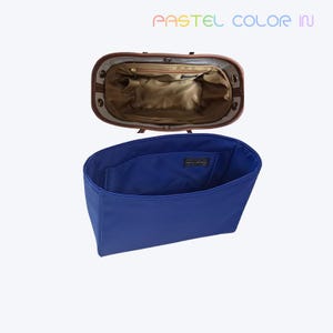 Könnte beinhalten: Eine offene Handtasche mit braunem Lederbesatz und einem blauen Innenorganizer. Das Innere der Handtasche ist beige, mit mehreren Taschen. Der Text "PASTEL COLOR IN" ist oben im Bild zu sehen.