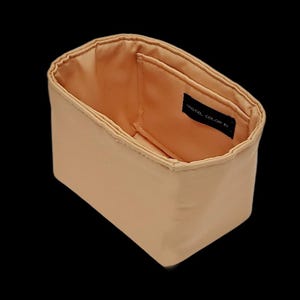 K&ouml;nnte beinhalten: Ein beigefarbener, rechteckiger Taschenorganizer mit passendem Innenraum. Der Innenraum verf&uuml;gt &uuml;ber eine kleine Tasche mit dem Text "PASTEL COLOR FU" auf einem schwarzen Etikett. Die Tasche ist oben offen und gibt den Blick ins Innere frei.