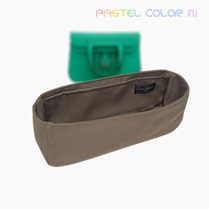 May include: A taupe handbag organiser with multiple compartments. The organiser has a rectangular shape and is made of a soft fabric. In the background, a green handbag is slightly out of focus. The text "PASTEL COLOR IN" is at the top.