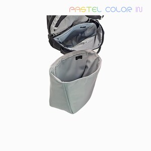 May include: An open black backpack with a light blue interior, showcasing multiple compartments. Below, a light blue bag organizer is displayed, offering a glimpse of its interior. The text "PASTEL COLOR IN" is visible at the top.