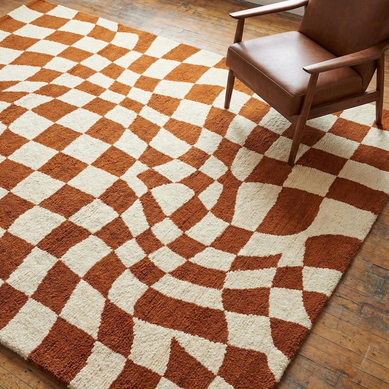 Modern rust and ivory checkerboard tufted rug in stylish living room with wooden chair and hardwood floor