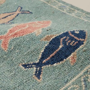Close-up of hand knotted wool rug showing dense knot structure, soft pile texture, and detailed fish pattern craftsmanship