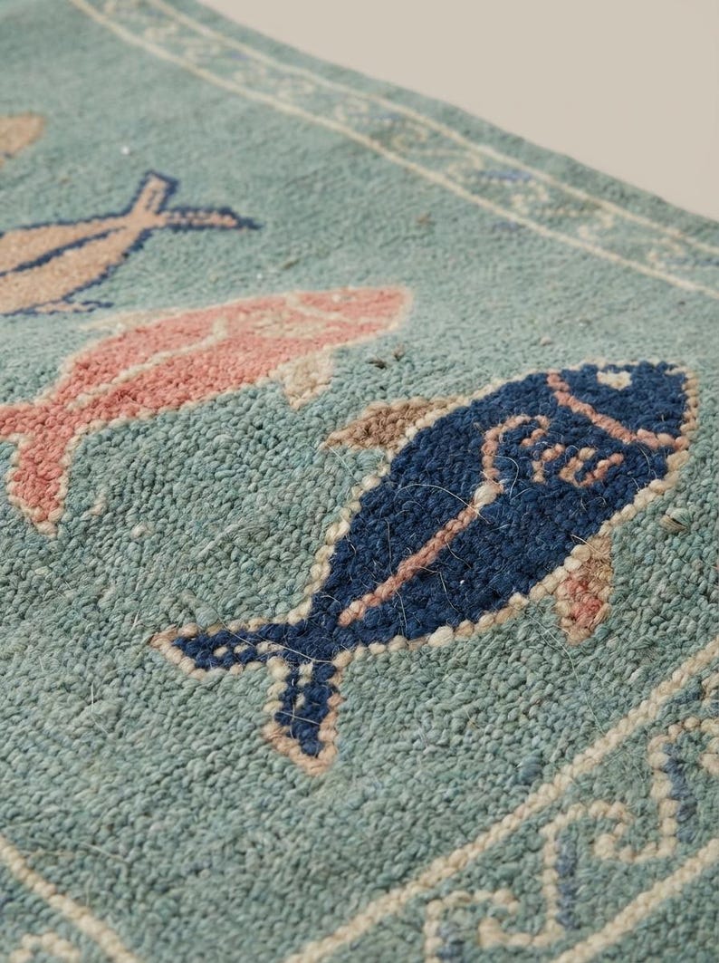 Close-up of hand knotted wool rug showing dense knot structure, soft pile texture, and detailed fish pattern craftsmanship