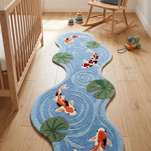 Puede incluir: Alfombra azul con forma de agua con peces koi y nen&uacute;fares. La alfombra tiene un fondo azul claro con un patr&oacute;n de agua arremolinada. Los peces koi son naranjas, negros y blancos. Hay nen&uacute;fares verdes dispersos.