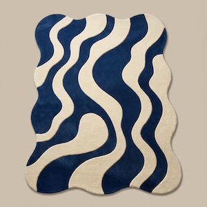 Unique shaped wavy rug in navy and cream tones, styled in a cozy living room with modern furniture and wooden flooring.