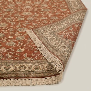 Artisan handmade rug with Persian inspired floral motifs and muted sage and beige accents