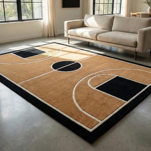 May include: A rectangular rug with a basketball court design. The rug has a tan playing surface with black and white court markings, a black border, and a black circle at the centre. The rug is placed on a concrete floor.